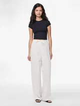 Pantalón blanco de tejido plano de algodón orgánico, corte ancho, tiro alto, largo hasta el tobillo, cintura elástica con cordón ajustable.