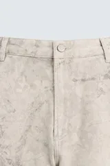 Bermuda de algodón color beige claro con efecto lavado y estampado abstracto en tonos grises. Diseño de corte relajado con cierre frontal de botón y cremallera, bolsillos delanteros y bolsillos traseros de plastrón.
