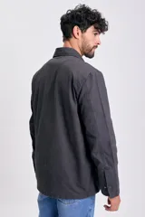 Campera de color negro para hombre, con cuello camisero, cierre frontal de botones y bolsillos aplicados en el frente.