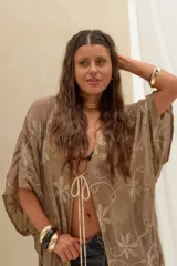 Kimono de corte amplio y mangas cortas, confeccionado en tela color caqui con delicados bordados florales en tono crudo. Cuenta con un cierre frontal con tiras largas terminadas en borlas.