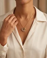 Collar de acero con baño de oro y delicada cadena fina, con un dije colgante en forma de corazón en relieve adornado con incrustaciones de circonias brilhantes.