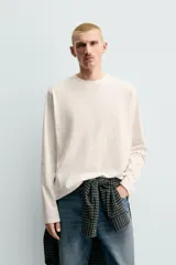 Camiseta de manga larga con corte relajado, confeccionada en tejido de algodón compacto. Presenta cuello redondo y detalle de costura en el centro de la espalda.