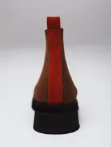 Bota tipo Chelsea de gamuza color marrón oscuro, con paneles laterales elásticos y suela de goma negra con taco bajo.