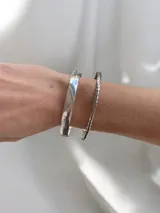 Pulsera tipo esclava rígida de diseño ancho y superficie lisa con acabado brillante.