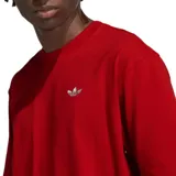 Remera de algodón color rojo con corte holgado, cuello redondo y mangas cortas. Presenta el logo de Adidas Originals bordado en el pecho y una etiqueta decorativa en el ruedo inferior.