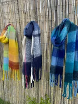 Bufanda larga con flecos, diseño a cuadros en tonos amarillos, naranjas, azules y celestes.