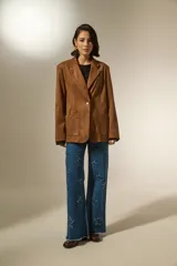 Blazer de gamuza color marrón, con cuello solapa, cierre frontal con un botón, bolsillos frontales tipo parche y diseño holgado.