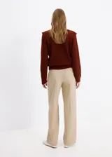Sweater marrón de punto con volantes en los hombros, cuello redondo y mangas largas.
