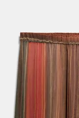 Pantalón semitransparente de tiro medio, corte bombacho con cintura y puños elásticos, con diseño de rayas verticales en tonos marrones y rojizos.