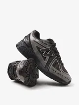 Championes New Balance modelo 1906R, de diseño técnico y retro-futurista. Presentan una base de malla transpirable con superposiciones texturizadas en tonos marrones y grises. Incorporan tecnología ABZORB en la mediasuela y sistema N-ergy para una amortiguación superior.