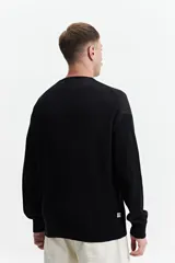 Buzo de punto oversize color negro, con escote redondo y puños.