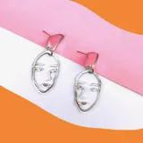 Par de aros colgantes plateados con forma de rostro minimalista.