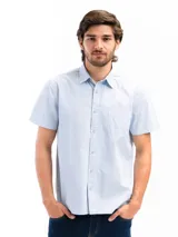 Camisa de manga corta color celeste claro, confeccionada en algodón, con cuello clásico y un bolsillo de parche en el lado izquierdo del pecho.