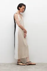 Vestido midi de lino color beige con laterales blancos, escote en V y cinturón negro con hebilla redonda.