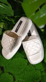 Sandalias bajas color beige con plataforma y tira ancha acolchada con diseño de rombos.