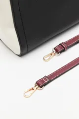 Cartera estructurada de símil cuero con diseño de bloques de color: principal en color camel, laterales en blanco y solapa frontal en negro. Posee correa larga regulable y desmontable.