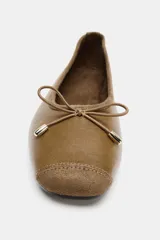 Zapato tipo bailarina de cuero color marrón, con punta redonda y detalle de lazo decorativo con herraje metálico en la parte delantera.