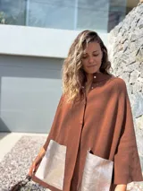 Saco tejido de punto en color marrón chocolate, con corte holgado y mangas anchas. Presenta cierre frontal con botones y dos bolsillos delanteros grandes en material metalizado color champán.