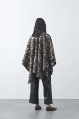 Poncho de silueta amplia con estampado animal print, bordes terminados con costura decorativa y diseño envolvente.