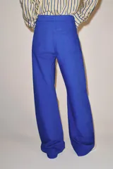 Jeans de tiro medio y corte barrel leg, de color azul, con diseño de cinco bolsillos y trabillas en la cintura. Cierre frontal con cremallera y botón metálico.