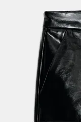 Shorts de tiro bajo confeccionados en material sintético con acabado efecto piel, cuentan con bolsillos delanteros y cierre frontal con cremallera y gancho metálico.