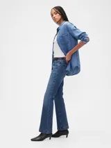 Jean de corte bootcut y tiro bajo, en color azul oscuro con acabado lavado. Presenta diseño de cinco bolsillos, cierre frontal con botón y cremallera, y costuras reforzadas en el ruedo.