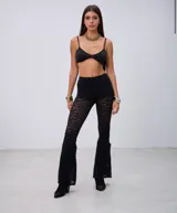 Pantalon de encaje negro con corte ajustado en la parte superior y botamanga acampanada, con diseño de encaje floral semitransparente.