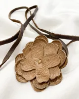 Gargantilla con dije de flor de cuero marrón y tiento de cuero marrón oscuro.