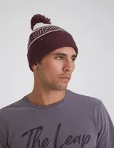 Gorro de lana tejido en jersey color bordó con pompón a tono.