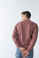 Buzo de felpa color rosa con logo estampado, cuello redondo, mangas largas y puños.