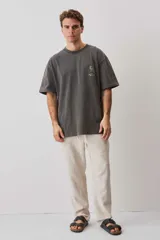 Remera gris oscuro oversize de corte relajado, con cuello redondo y mangas cortas. Presenta un pequeño estampado sutil en el pecho.