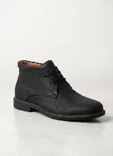 Bota corta tipo chukka de cuero negro con cordones al tono, diseño minimalista y suela plana.