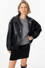 Chaqueta de cuero sintético con textura granulada, corte oversize, cuello camisero, cierre frontal con botones a presión, bolsillos frontales tipo cargo y detalles de charreteras en los hombros.