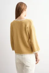 Sweater de punto negro con escote bote, mangas largas y detalles de terminación en ondas de color blanco en el cuello, los puños y el ruedo.