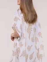 Kimono de gasa verde con estampado de hojas blancas y detalles de lurex. Presenta mangas cortas holgadas, diseño abierto al frente y terminación en punta con borlas en el ruedo.