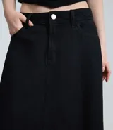 Falda larga de denim color negro, con corte evasé, cintura media, cierre frontal con botón y cremallera, bolsillos funcionales y bajo desflecado.