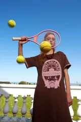 Vestido marrón holgado con estampado frontal y mangas cortas con terminación de crochet. Incluye una funda de raqueta de tenis y una raqueta de tenis rosa.
