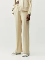 Pantalón recto color beige de tejido Peach-T, suave y elástico, con bolsillos laterales, costura vertical frontal y cordones de ajuste en la cintura.