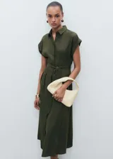 Vestido midi de corte evasé en color verde oliva, con cuello camisero, cierre frontal de botones y mangas cortas con dobladillo. Incluye un cinturón de la misma tela para ajustar a la cintura y detalle de pinzas delanteras.