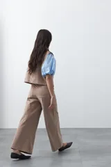 Pantalón de pana de corte wide leg, color marrón oscuro, con calce relajado y detalle de bordado en el borde de los bolsillos delanteros.