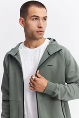 Campera con capucha y cierre frontal, color beige, con detalles de costuras y cierres en negro. Presenta mangas largas con puños acanalados y logo pequeño en el pecho.