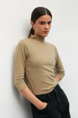 Polera de algodón color blanco, con cuello alto y mangas tres cuartos. Presenta un diseño ajustado al cuerpo con costuras decorativas en las sisas.