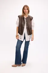 Chaleco de cuero sintético negro, con cierre frontal de botones a presión, bolsillos laterales y ruedo regulable con cordón elástico.