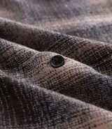 Camisa de manga larga confeccionada en franela de algodón, con diseño de cuadros, cuello inglés, cierre frontal con botones y un bolsillo en el pecho.