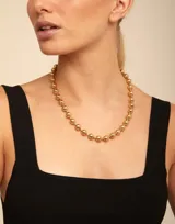 Collar de cuentas esféricas metálicas con baño de oro de 18k, con cierre de tipo hormiga.