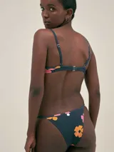 Bikini azul con estampado abstracto en tonos naranja y rosa. El corpiño tiene corte clásico con breteles finos y la bombacha es de tiro bajo con tiras finas regulables.