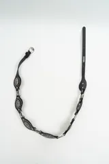 Cinturón negro de cuero con apliques metálicos plateados en forma de óvalo y hebilla metálica. Presenta el logo de la marca estampado en el extremo.