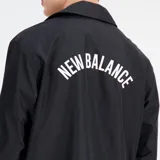 Campera negra tipo coach de New Balance, con cierre de botones a presión, corte relajado, mangas largas y logo blanco estampado en el pecho.
