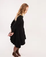 Vestido corto marrón con cuello camisero, abotonado en el frente, mangas largas con elástico en los puños y falda escalonada con volados.