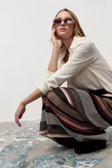 Falda midi de tejido de punto con diseño de rayas horizontales en tonos tierra, marrón, negro y beige. Presenta un corte recto y tiro alto.